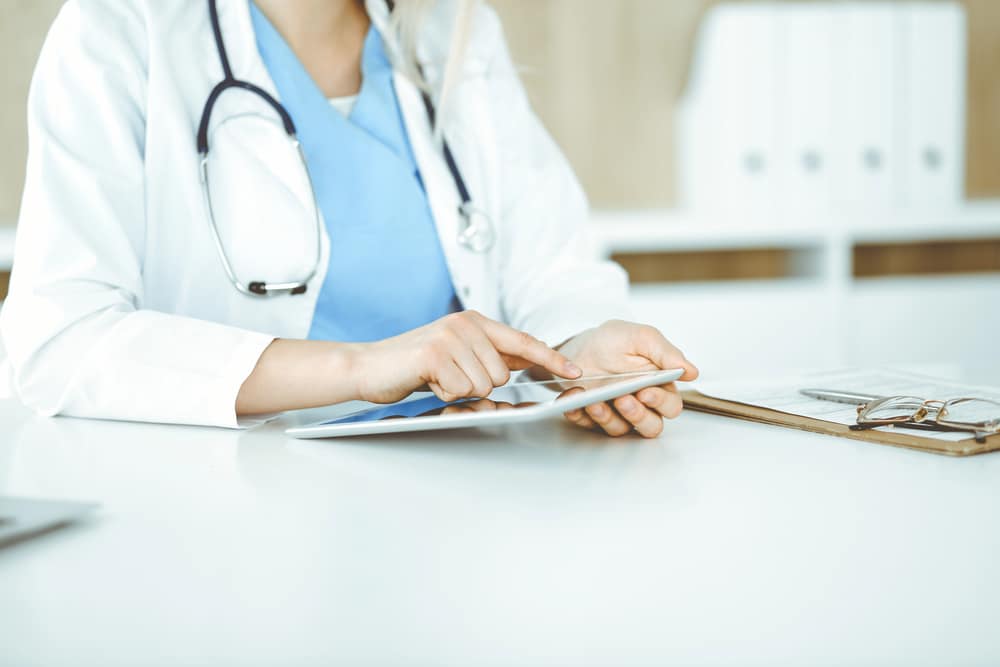 Female doctor with stethoscope uses an ipad.